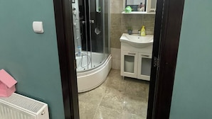 Een badkamer met een douche, wastafel en spiegel.
