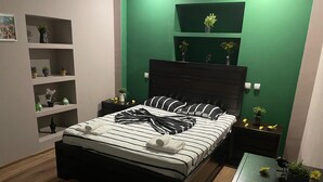 Een moderne slaapkamer met een bed, nachtkastjes, een dressoir en groene wanden.