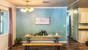 Un'area pranzo con un tavolo in legno e panche, un lampadario e un quadro appeso al muro.