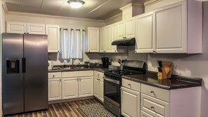 Una cucina moderna con mobili bianchi, elettrodomestici in acciaio inossidabile e un tappeto decorato.