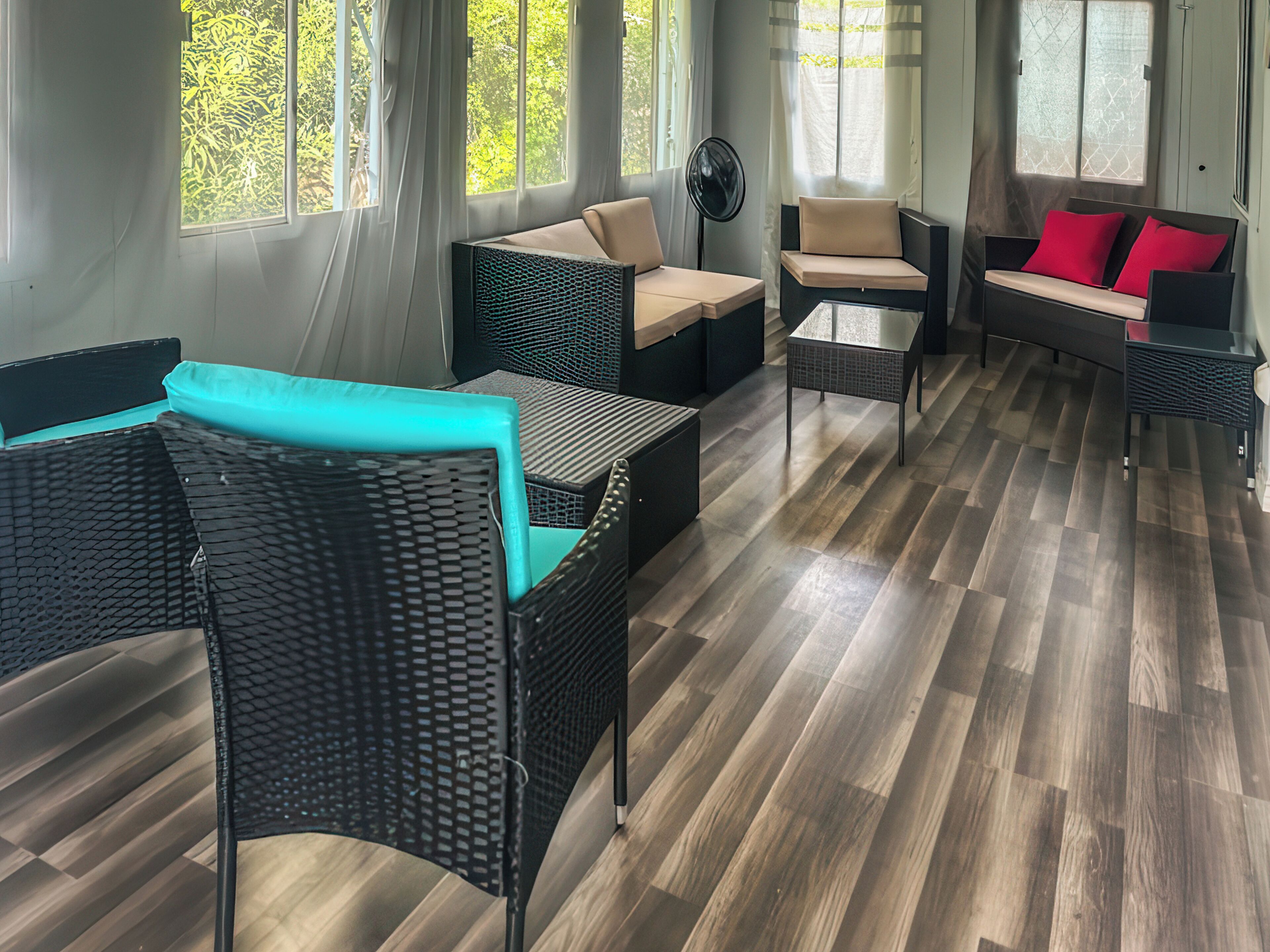 Un espace de détente moderne, avec des meubles en osier, une table basse en verre et un plancher en bois.