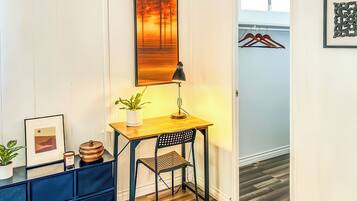 A small room with a desk, chair, lamp, potted plant, and framed picture.