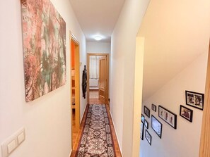 A hallway with a patterned carpet, a large abstract painting on the left wall, and several framed pictures on the right wall. - Charming Bungalow Rental in Alcalá de la Selva, Spain (Alcala de la Selva)