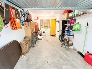 A narrow hallway with bicycles, a washing machine, and various storage items.
