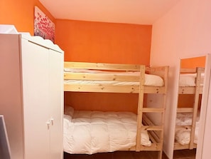Habitación con literas, un armario y un cuadro en la pared.