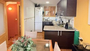 A compact kitchen with dark cabinets, a white refrigerator, and a small countertop. - Charming Bungalow Rental in Alcalá de la Selva, Spain (Alcala de la Selva)