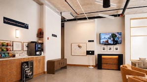 A modern refueling station with a coffee machine, seating area, and a television displaying a cityscape. - Roami at Studio 135 - Modern Studio (Denver)