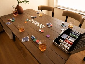Una mesa de madera con fichas de póker, cartas y vasos de whisky.