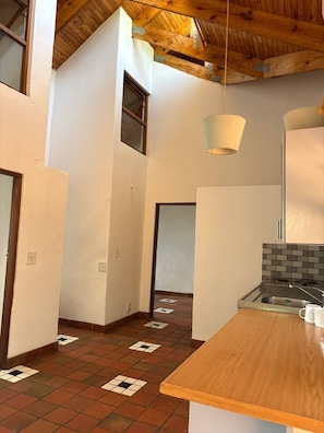 A kitchen with a wooden countertop, a hanging light fixture, and a tiled floor.