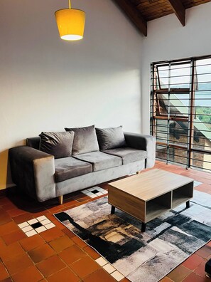 A modern living room with a grey sofa, a wooden coffee table, and a patterned rug. - Nice Cozy Apartment With a Great dam View (Hartbeespoort)