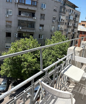 A multi-story building with balconies, air conditioning units, and a tree in the foreground. - White Pearl Apartment (București)