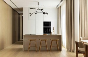 A modern kitchen with a central island, wooden stools, a hanging light fixture, and a dining area with a table and chairs. - A PERFECT BLEND OF CONTEMPORARY ELEGANCE, COMFORT & PARISIAN CHARM- MADELEINE (Paris)