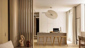 Una cocina moderna con una isla central, taburetes de madera y una lámpara colgante.