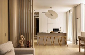 A modern kitchen with a central island, wooden stools, and a pendant light. - A PERFECT BLEND OF CONTEMPORARY ELEGANCE, COMFORT & PARISIAN CHARM- MADELEINE (Paris)