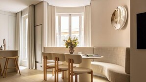 Una sala moderna con una mesa redonda para comer, cuatro sillas, un sofá y un elemento decorativo en la pared.