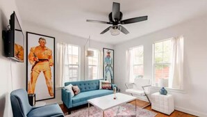 Un salon avec un canapé bleu, un fauteuil blanc et une table basse.