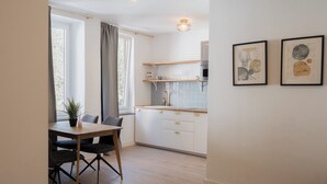 A modern kitchen with white cabinets, a wooden countertop, and a dining area with a table and chairs. - Aparthotel Hirschenhof (Spital am Semmering)