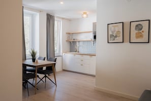 Une cuisine moderne avec des meubles blancs, un plan de travail en bois et un coin repas comprenant une table et des chaises.