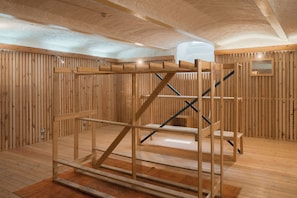 A wooden interior with a bunk bed structure, wooden walls, and a vaulted ceiling.