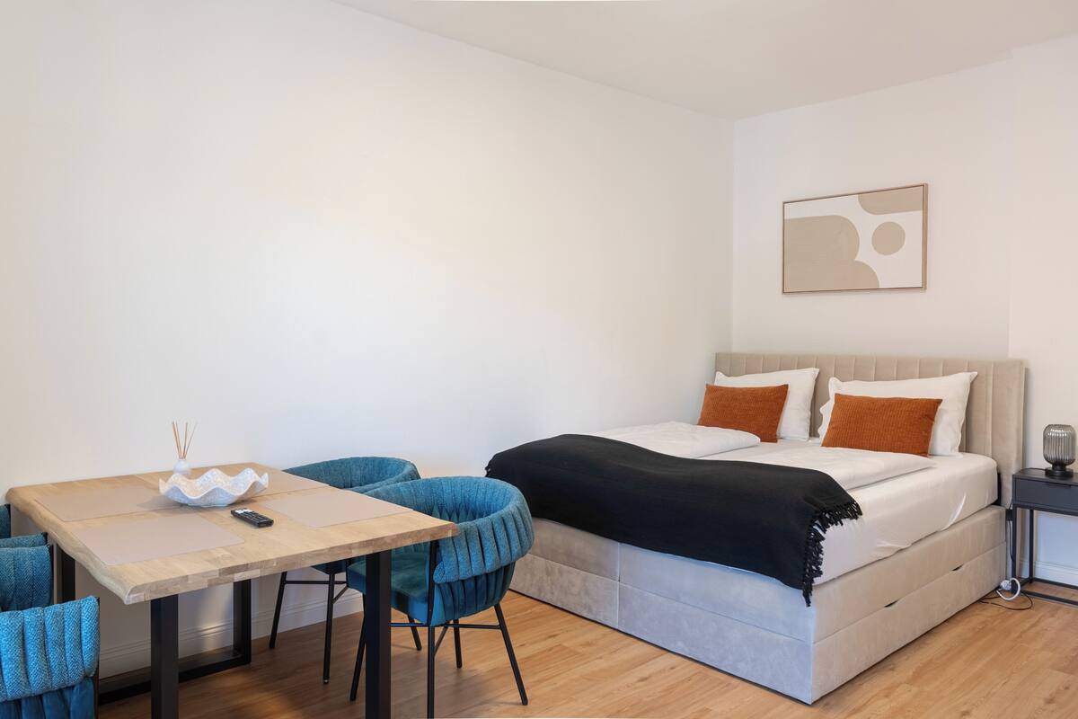A modern bedroom with a bed, bedside table, and a small table with chairs.
