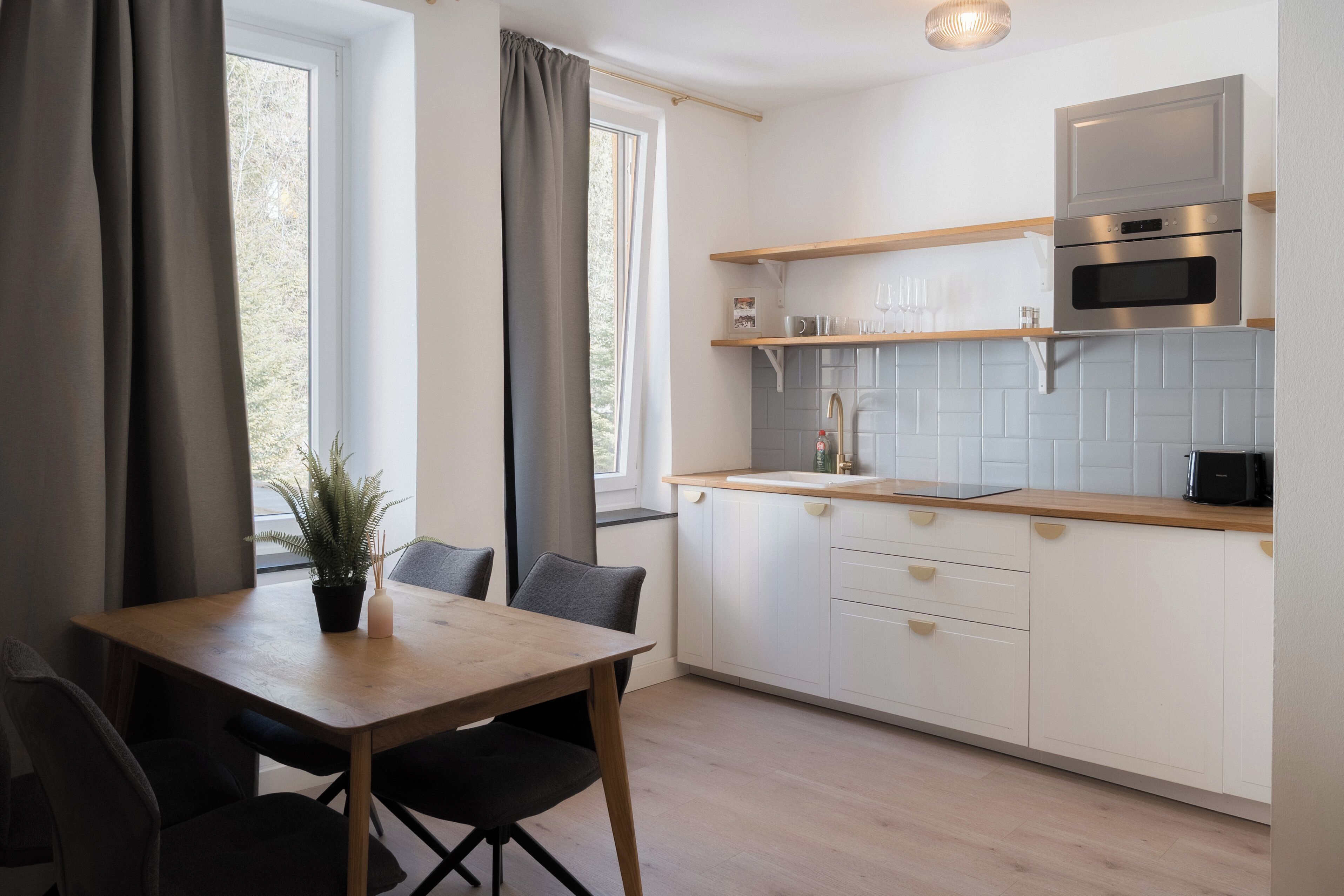 Una cocina moderna con armarios blancos, encimera de madera y horno empotrado.