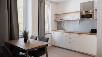 Una cocina moderna con armarios blancos, encimera de madera y horno empotrado.