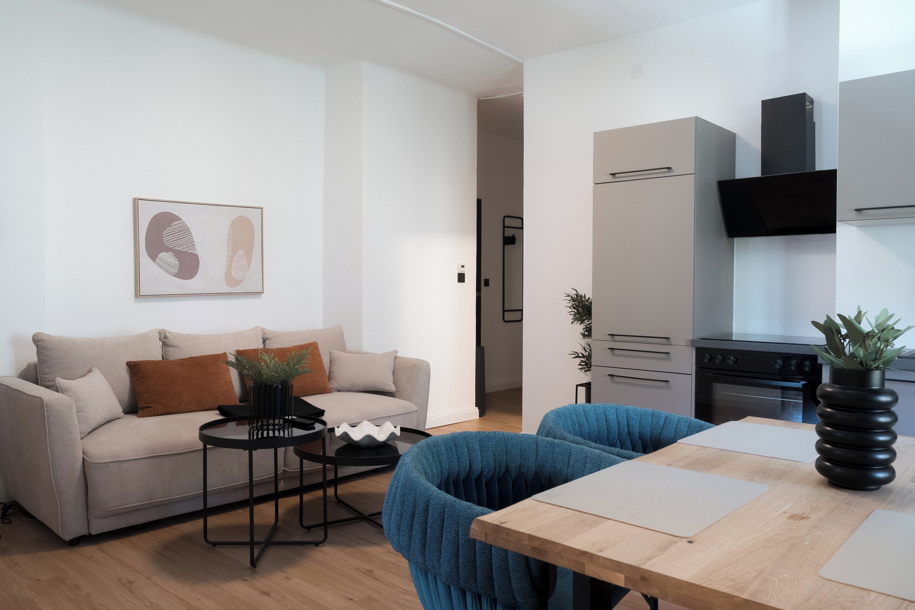 A modern living room with a sofa, a coffee table, and a dining area with chairs.