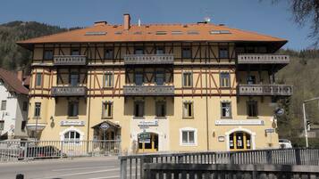 A two-story building with a yellow facade, multiple balconies, and a sign for 'Hirschenhof Restaurant.'