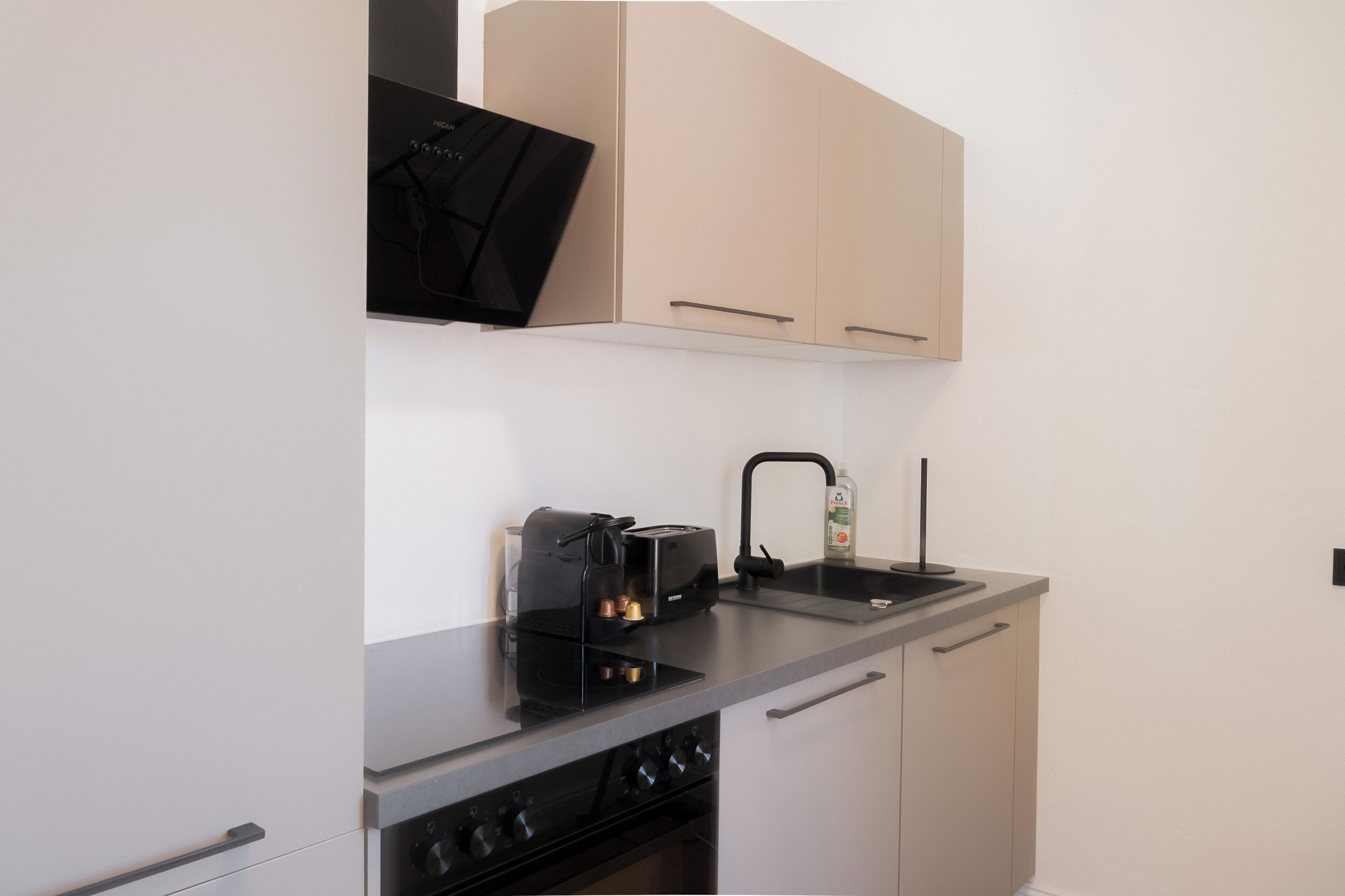 Cocina compacta con estufa, pileta y cafetera.