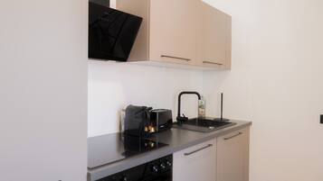 Cocina compacta con estufa, pileta y cafetera.