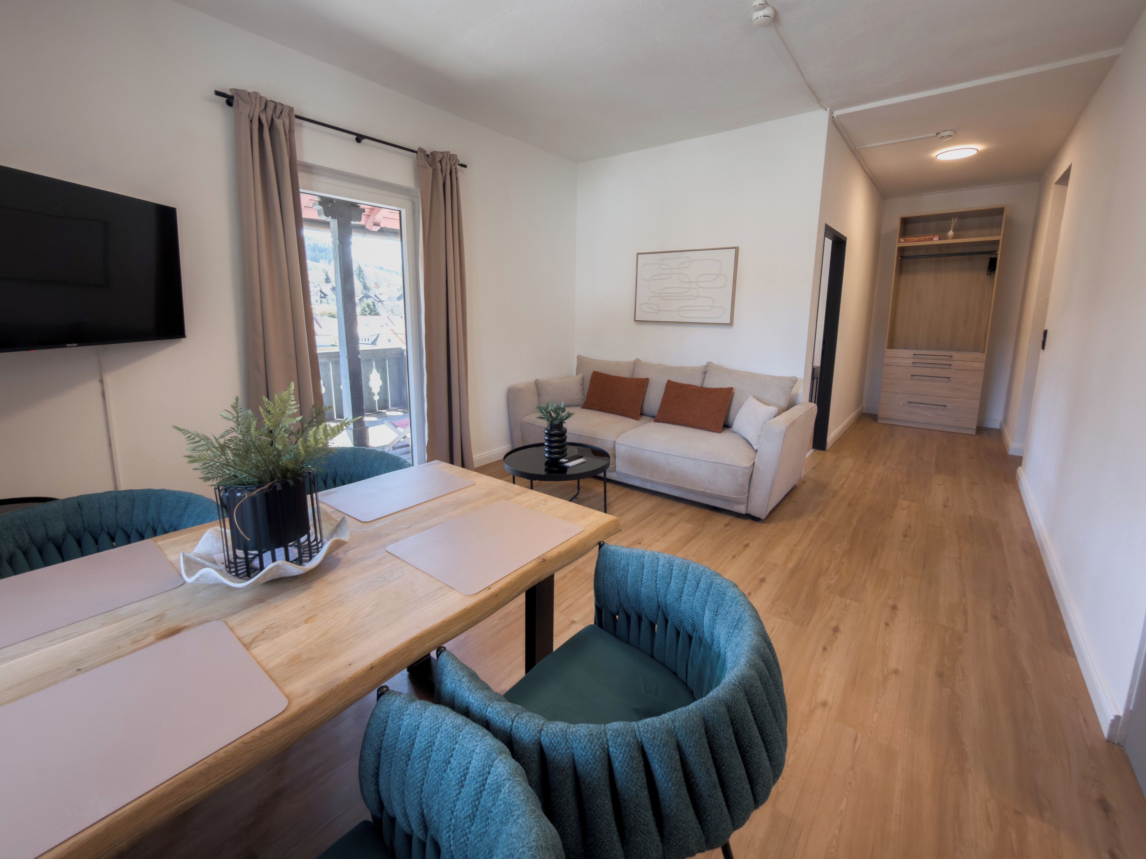 Ein modernes Wohnzimmer mit Sofa, Couchtisch und Essbereich mit Stühlen und Tisch.