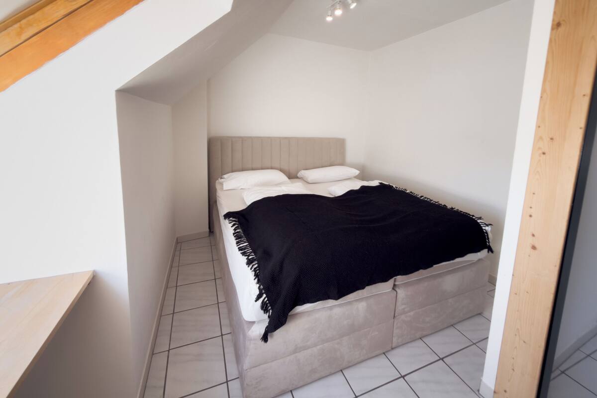 A bedroom with a bed, a headboard, and a ceiling light fixture.