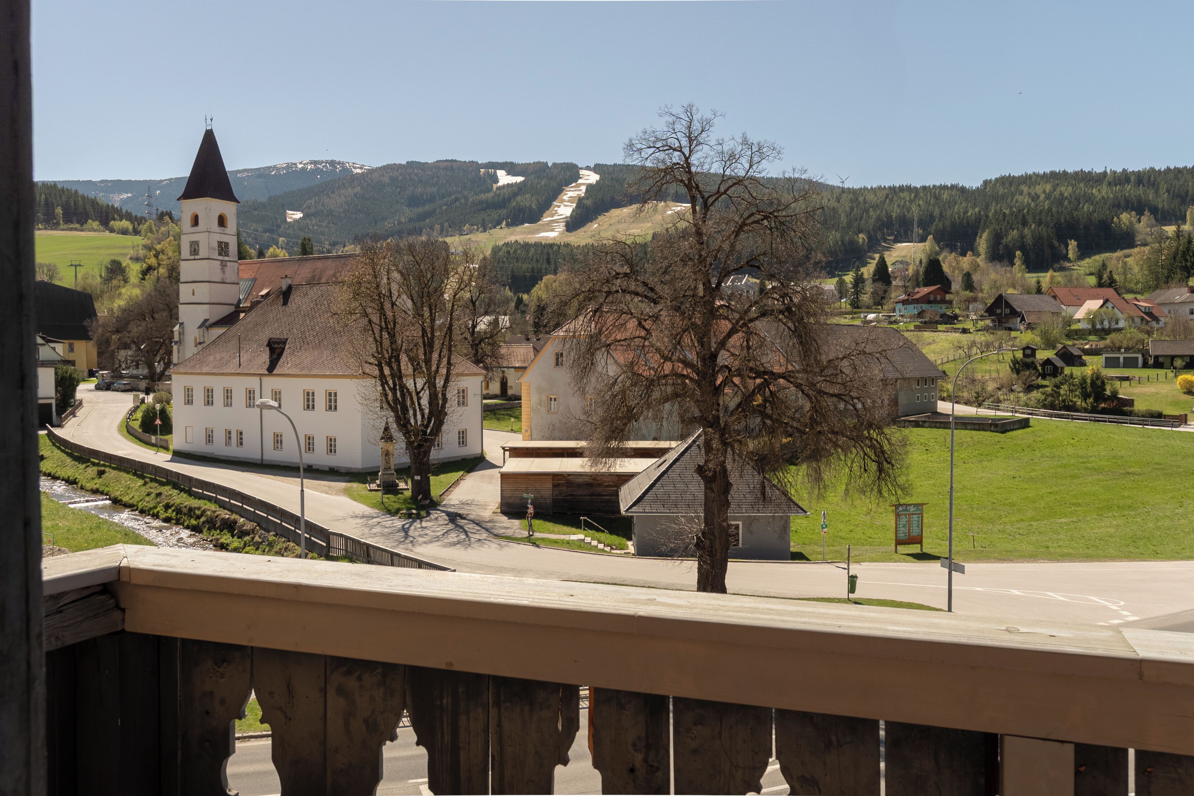 A town with a prominent church, a bridge, and a mountain in the background.