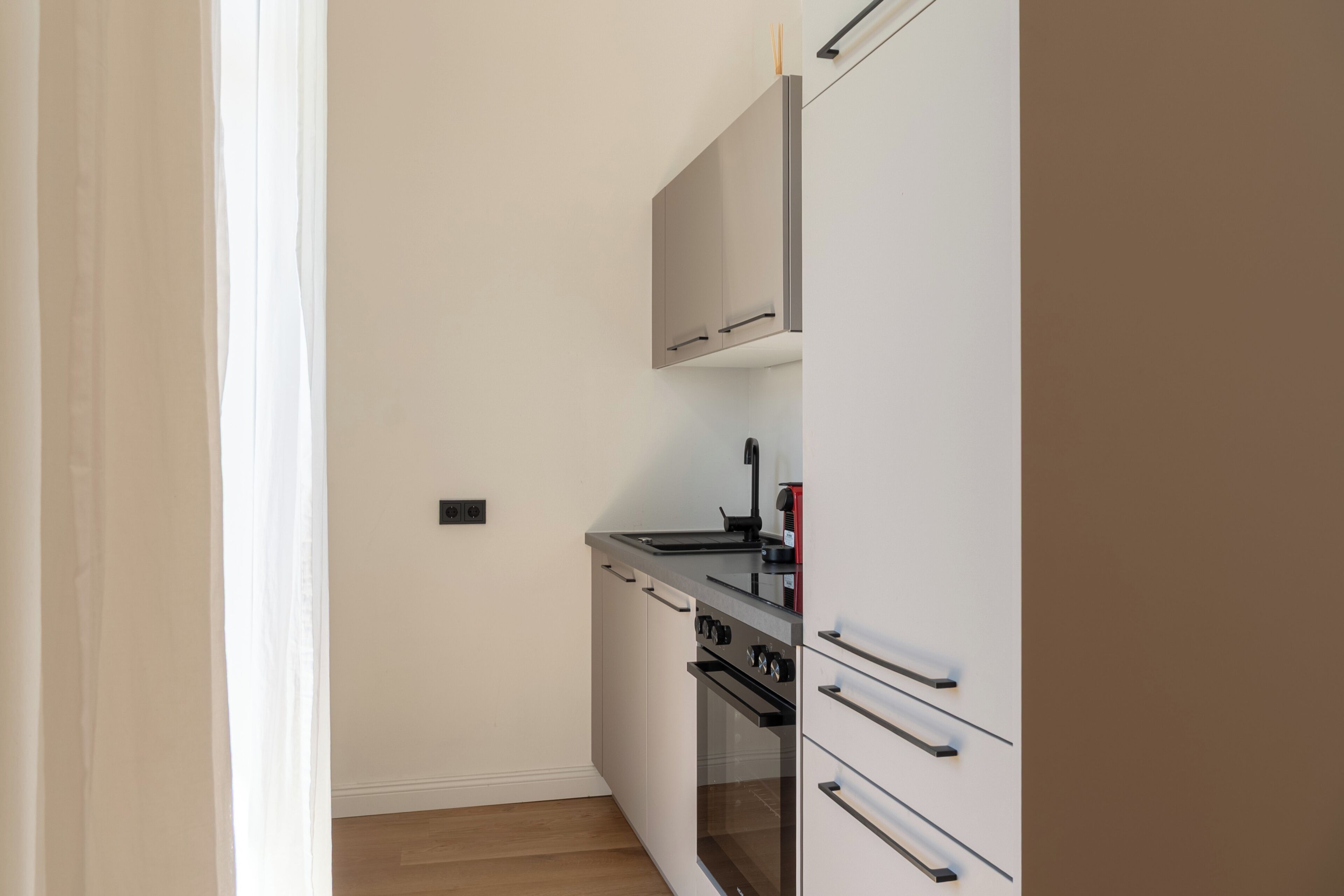 Een keuken met een fornuis, oven en kastjes.