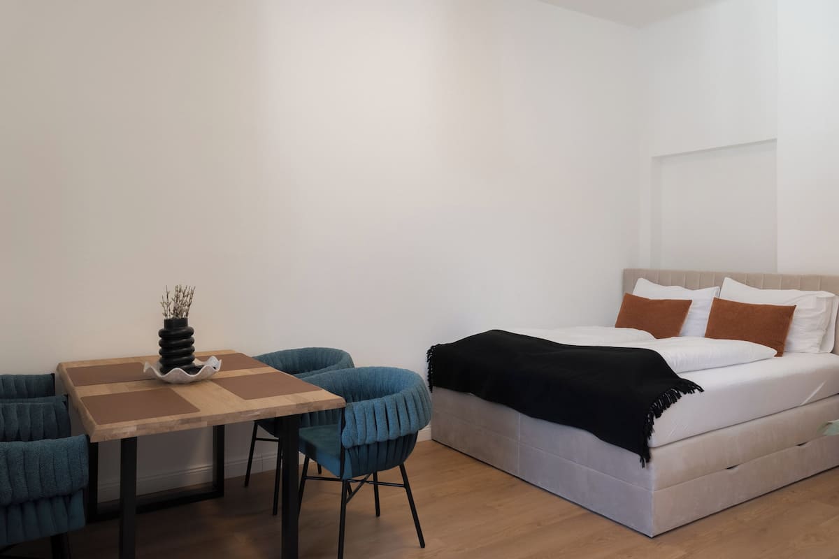 A bedroom with a bed, a table, and two chairs.