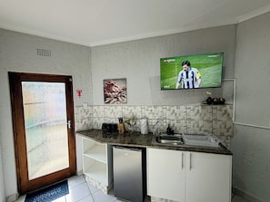 Eine Küche mit Einbaukühlschrank, Spüle und Wandfernseher, der ein Fußballspiel zeigt.