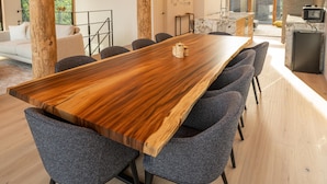 Un comedor amplio con una larga mesa de madera, seis sillas tapizadas y un ventilador de techo.
