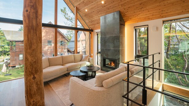 Un interior moderno con techo de madera, una chimenea grande, un sofá y una escalera.