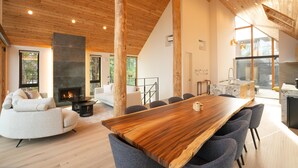Un espacio habitable amplio con un gran comedor de madera, chimenea y cocina moderna.