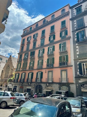 A multi-story building with balconies, a church, and parked cars. - COMFORT AND ELEGANCE IN AN OASIS OF PEACE IN THE BEATING HEART OF NAPLES. (Napoli)