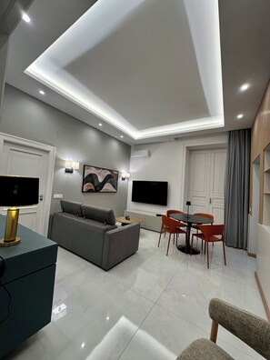 A modern living room with a sofa, TV, dining table, and chairs. - COMFORT AND ELEGANCE IN AN OASIS OF PEACE IN THE BEATING HEART OF NAPLES. (Napoli)