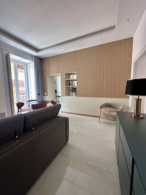 A modern living room with a sofa, a chair, a table, and a lamp. - COMFORT AND ELEGANCE IN AN OASIS OF PEACE IN THE BEATING HEART OF NAPLES. (Napoli)