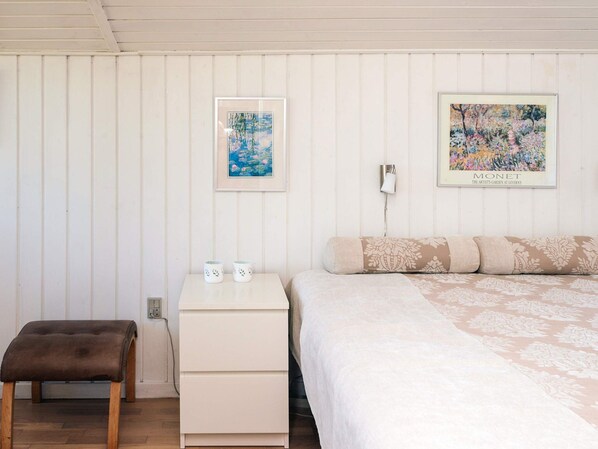 A bedroom with a bed, a nightstand, a bench, and two framed artworks on the wall. - 4 Person Holiday Home in Hejls (Hejls)
