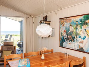 A dining area with a wooden table, chairs, a vase with dried plants, a board game, and a painting on the wall. - 4 Person Holiday Home in Hejls (Hejls)