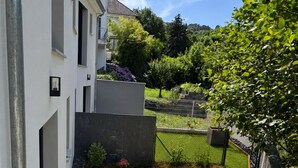 Een terras met een tafel, stoelen, een waterslang en een gazon.