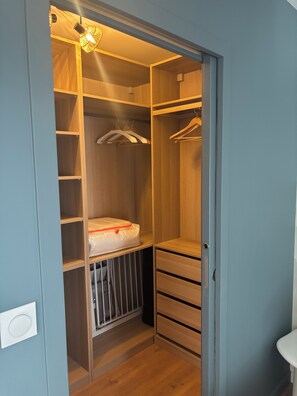 A walk-in closet with wooden shelves, a hanging rod, and a padded storage unit.