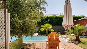 Una terraza de madera con una silla, una piscina y una cerca de madera.