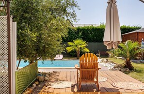 A wooden deck with a chair, a pool, and a wooden fence. - Comfort Opale Room with Shared Pool (Saint-Cyr-sur-Loire)