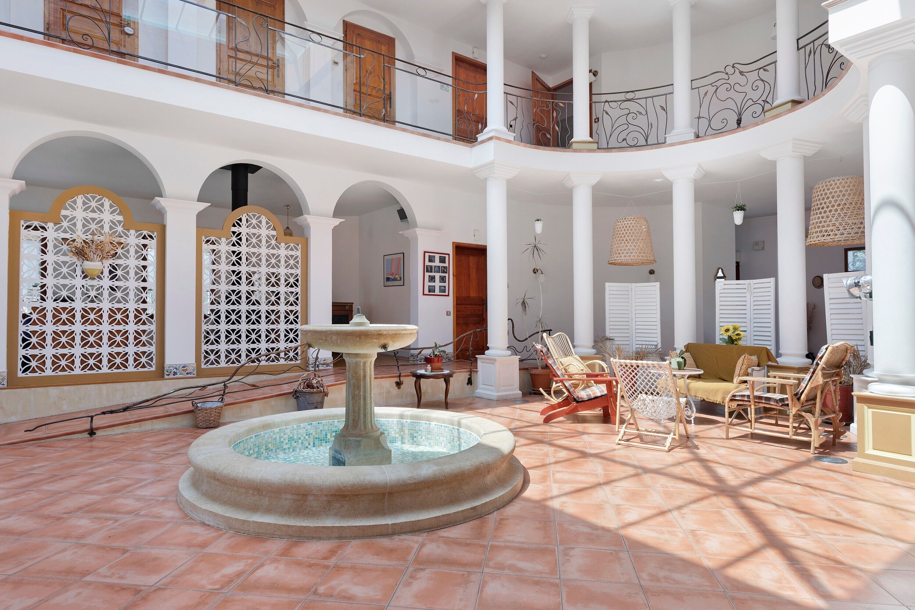 A spacious courtyard with a central fountain, multiple seating areas, and a balcony with decorative railings.