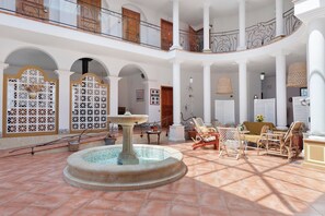 A spacious courtyard with a central fountain, multiple seating areas, and a balcony with decorative railings. - Comfort Opale Room with Shared Pool (Saint-Cyr-sur-Loire)